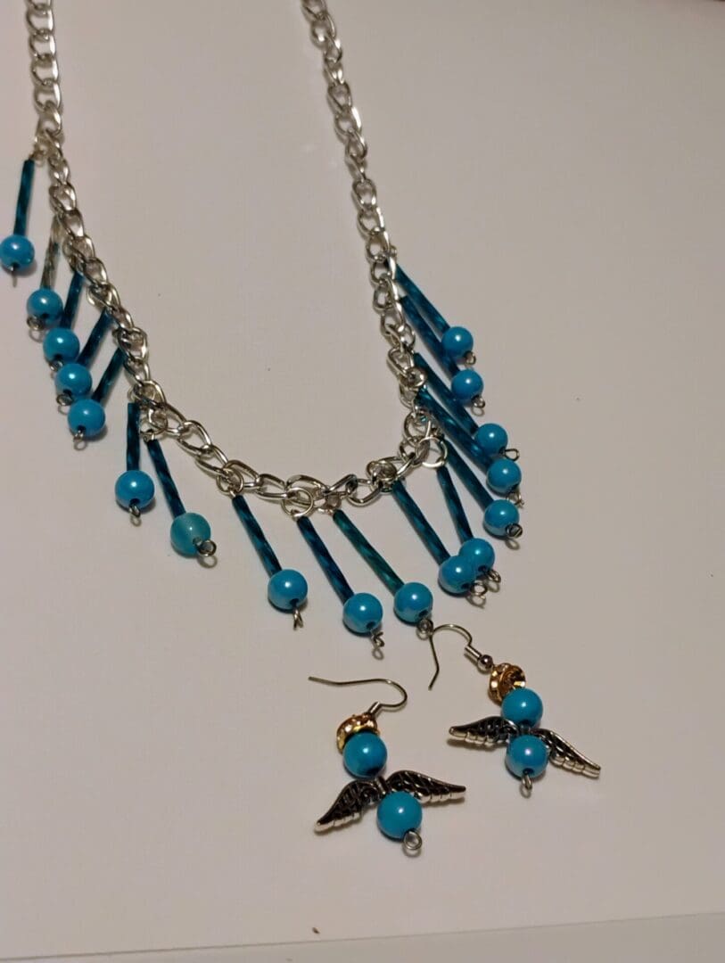 Silver chain necklace with blue bead accents and dangling charms.