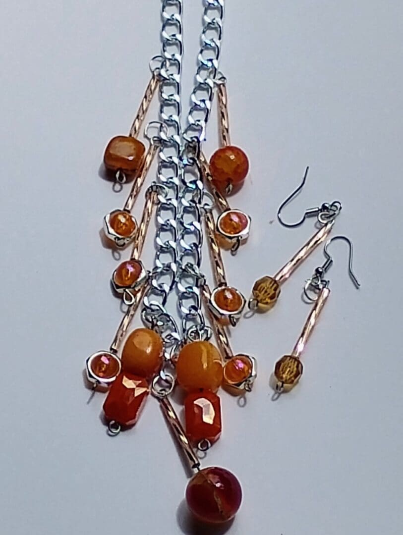 Handmade jewelry with orange and amber beads on a silver chain and matching earrings.